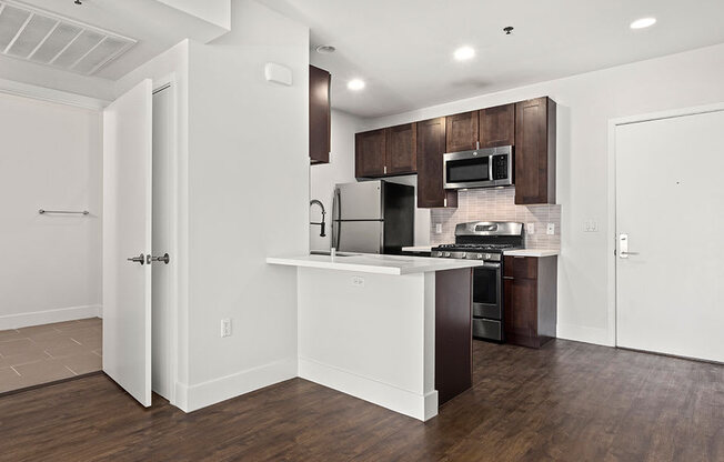 Tiled kitchen with stained wood cabinets and stainless steel appliances.