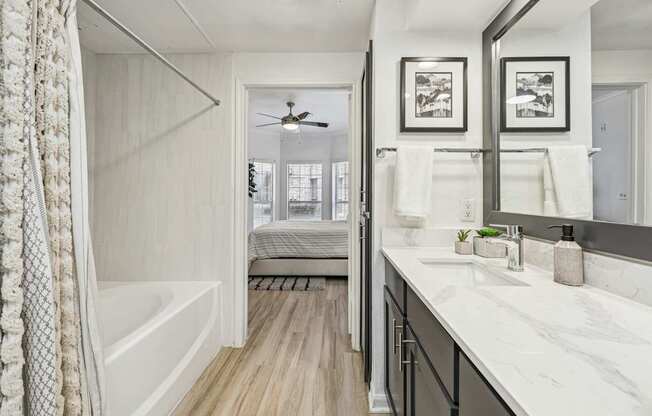 A bathroom with a white tub and marble countertops.