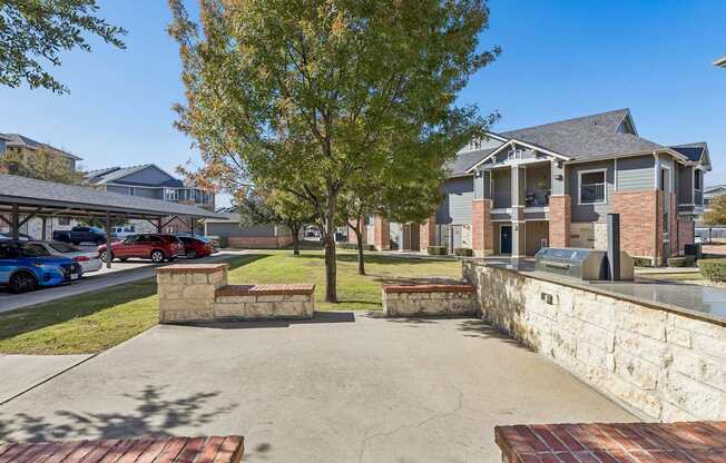 A tree in a courtyard with a house in the background.