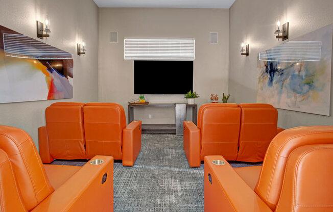 A room with orange chairs and a television.