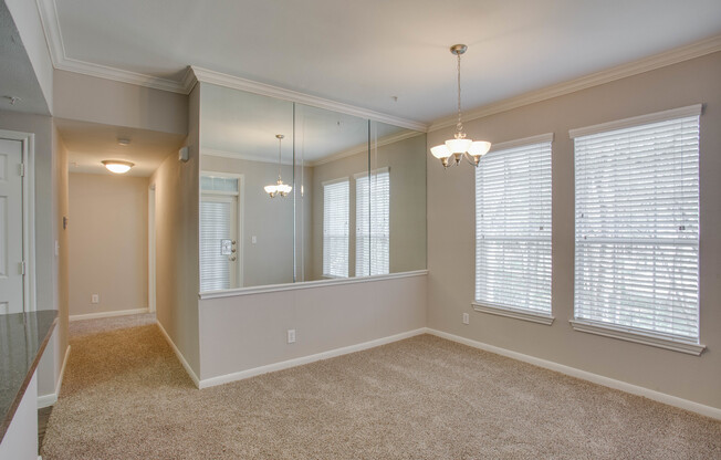 View of Dining Area with Hanging Light, Mirrors, and Carpet at Raveneaux Apartments