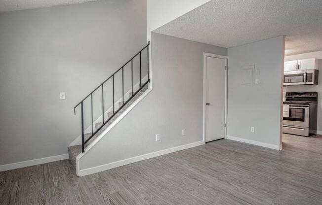 A room with a staircase and a door leading to a kitchen.