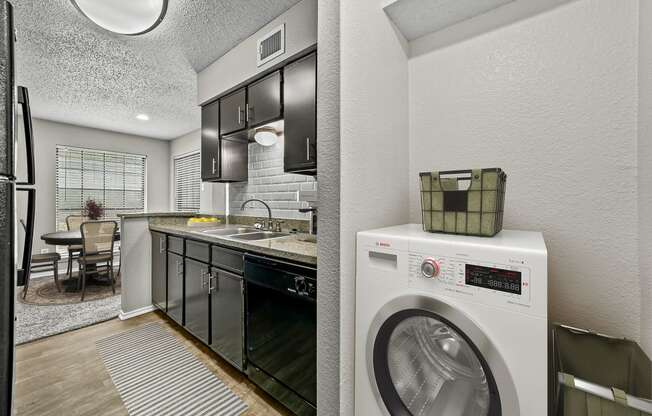 a kitchen with a washing machine and a washer and dryer at Legacy Apartments in Plano, TX