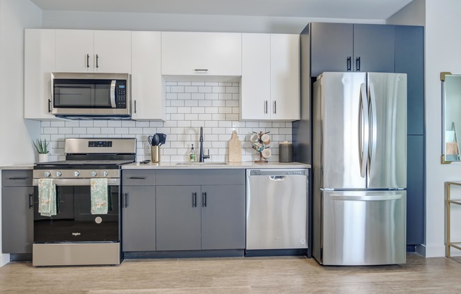 Modern kitchens outfitted with stainless steel appliances and quartz countertops with tile backsplashes.