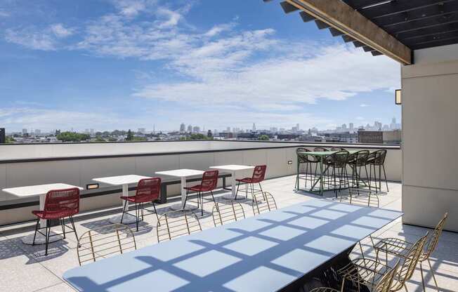 A patio with tables and chairs overlooking a city skyline.