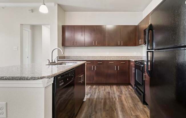 A kitchen with dark wood cabinets and black appliances.