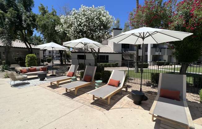 Enjoy our courtyard's lounge chairs and shaded umbrellas for a relaxing outdoor retreat at Boulders at Lookout Mountain Apartment Homes, Phoenix, AZ