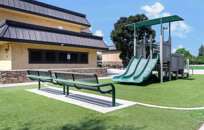 a playground with a slide and a bench in front of a building