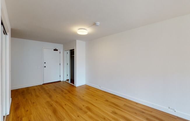 a bedroom with hardwood floors and white walls