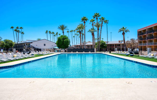 a large pool with palm trees in front of a hotel at Presidio Palms Apartments, Tucson