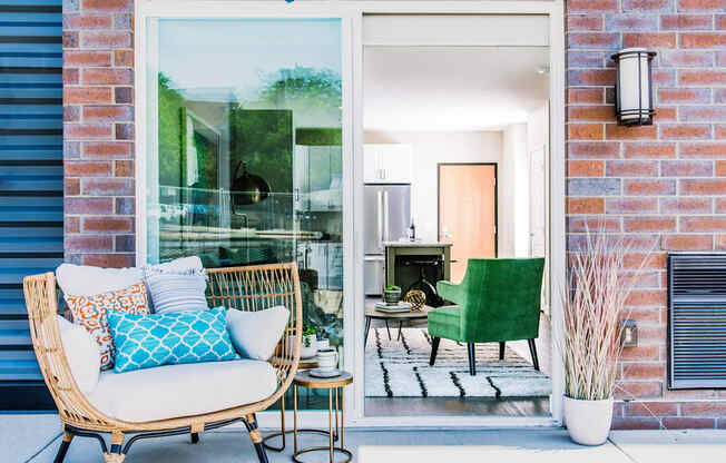 Cozy one-bedroom apartment patio accessible from the kitchen area through a sliding door. The outdoor space features a small seating area for relaxation or outdoor dining.