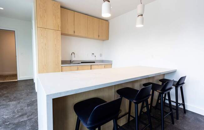 a kitchen with a white counter top and black bar stools