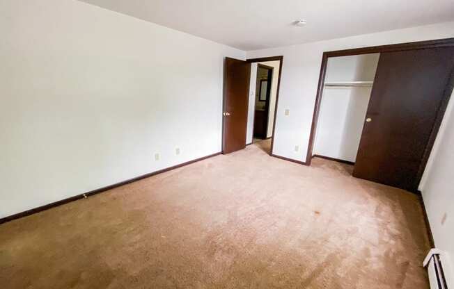 an empty living room with a wooden floor and a door to a closet