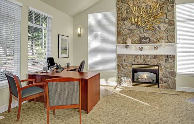 a room with a fireplace and a desk and chairs