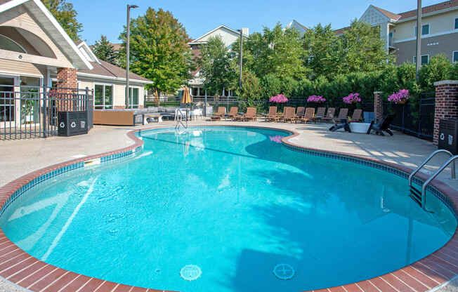 a large pool with chairs and a building in the background