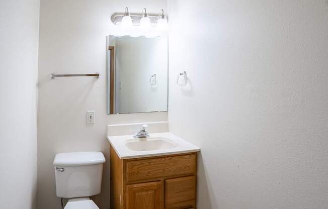 A white toilet sits next to a sink in a small bathroom. West Fargo, ND Sheyenne Terrace Townhomes