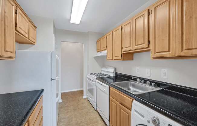 a kitchen with wood cabinets and black counter tops and white appliances