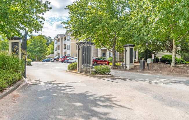 A street view with cars parked on the side and trees lining the road.