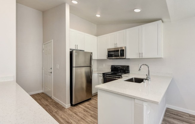 Kitchen with Dishwasher , Hardwood Inspired Floor, Oven, Microwave, White Cabinets  and Refrigerator