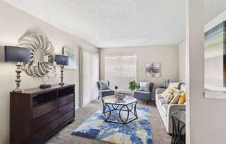 A living room with a white couch, a coffee table, and a large mirror on the wall.