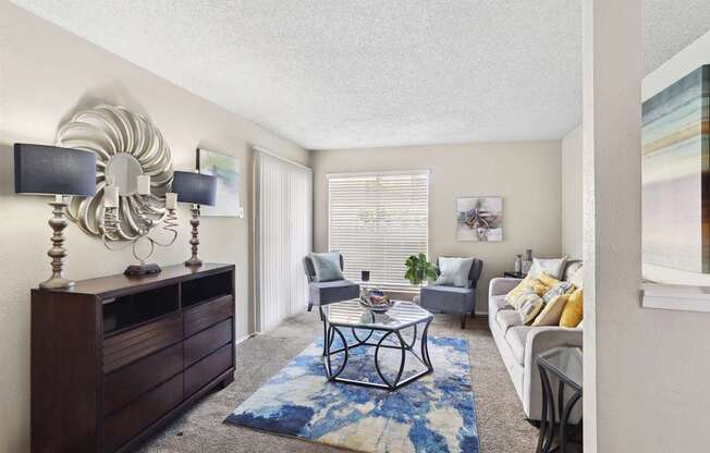 A living room with a white couch, a coffee table, and a large mirror on the wall.