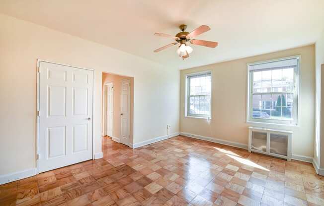 vacant living area with hardwood flooring, ceiling fan, and large windows  at 1401 sheridan apartments in washington dc