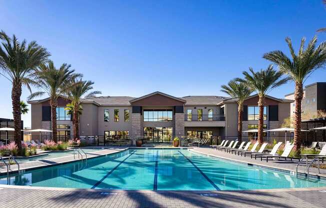 A large swimming pool in front of a building with palm trees.