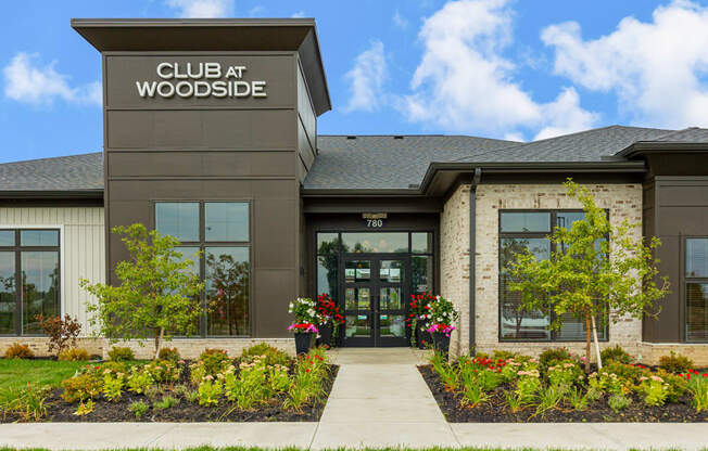 the front of a club at woodside building with a sidewalk and plants