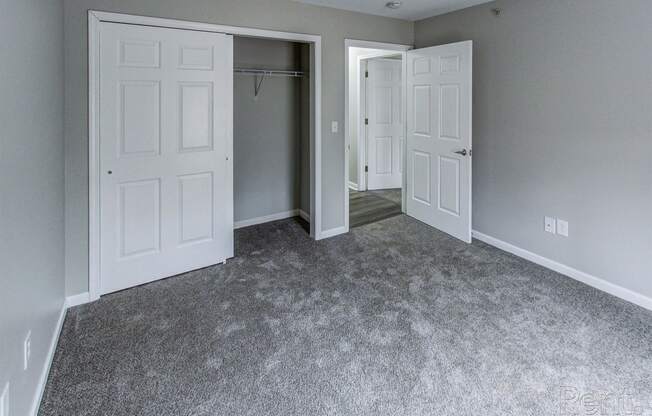 an empty bedroom with white doors and a carpeted floor