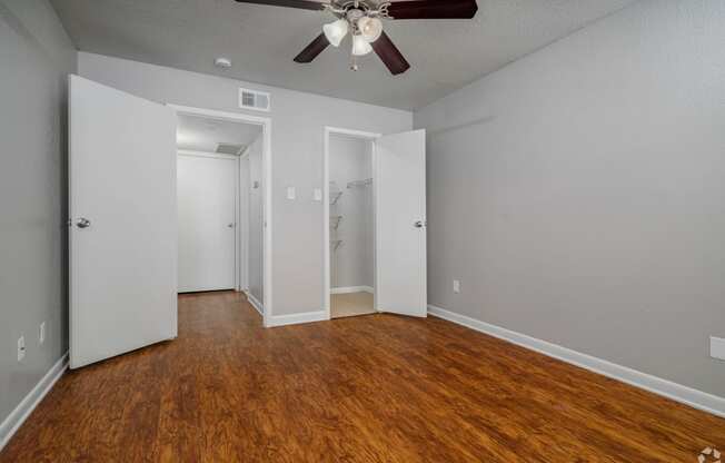 the living room of an empty house with wood flooring and a ceiling fan