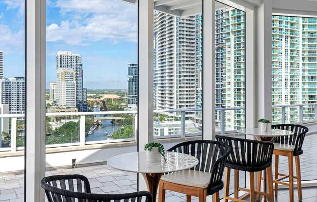 A table with chairs is set up on a balcony overlooking a city.
