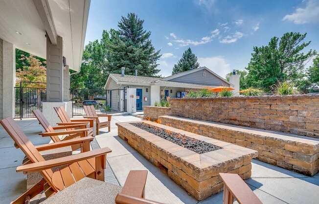 A patio with wooden chairs and a fire pit.