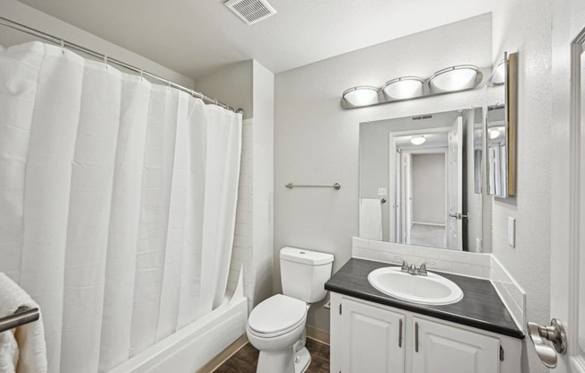 a white bathroom with a shower and a sink and a toilet