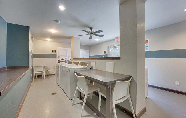 A kitchen with white appliances and white chairs.