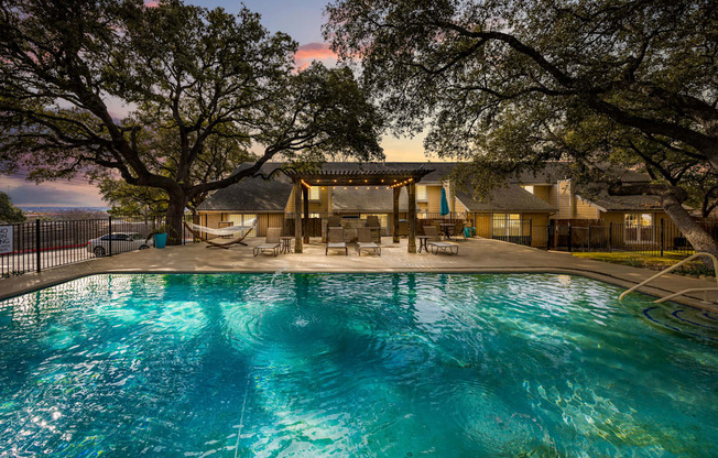 A large swimming pool in front of a house surrounded by trees.