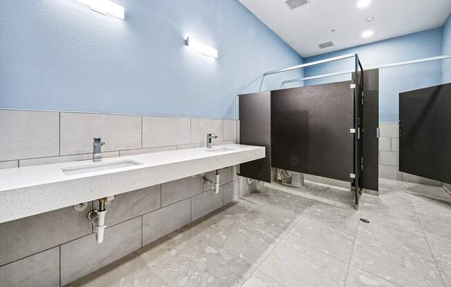 A public restroom with a row of sinks and a row of stalls.