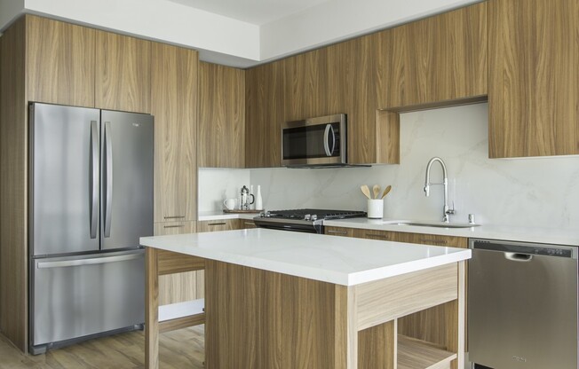 Interior kitchen with warm brown cabinetry, stainless steel appliances, and beautiful backsplash