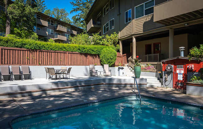 A pool with pool chairs and surrounded by apartment buildings