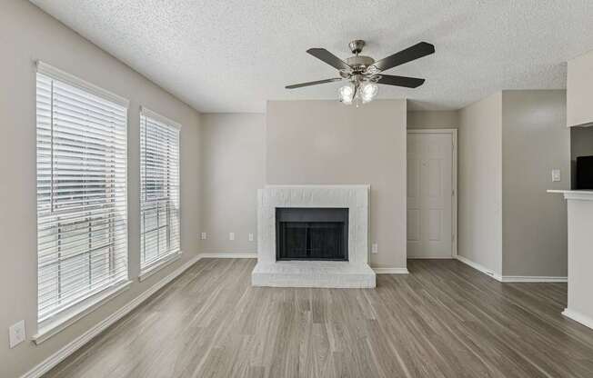 A living room with a fireplace and a ceiling fan.