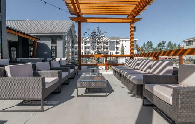 a patio with couches and tables and a wooden canopy