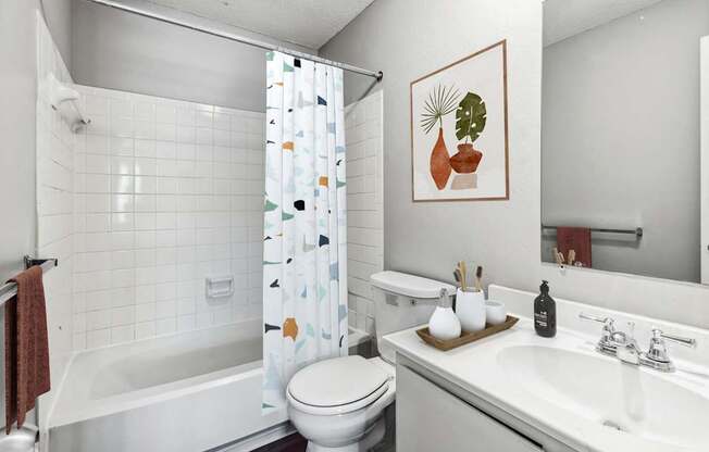 A white bathroom with a toilet, sink, and shower.