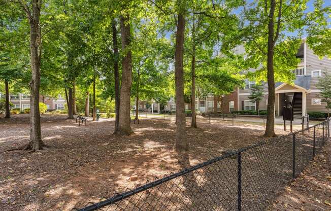 a fenced in dog park with trees and houses