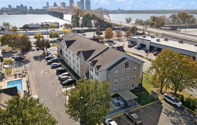 an aerial view of a building with a river and a city in the background