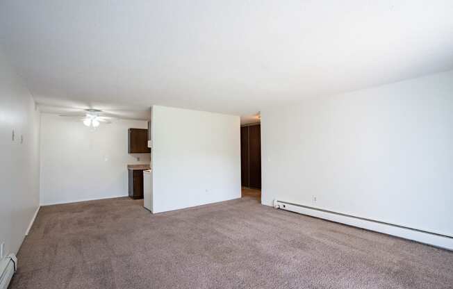 an empty living room with white walls and carpet. Coon Rapids, MN Robinwood Apartments