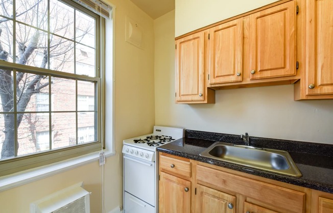 kitchen with gas range, wood cabinetry and large window  at 1401 sheridan apartments in washington dc