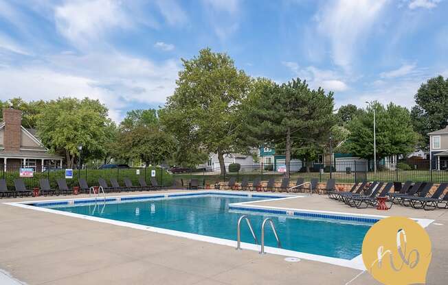 A large outdoor swimming pool surrounded by trees and lounge chairs.