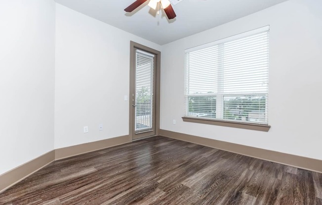 an empty bedroom with a window and a ceiling fan