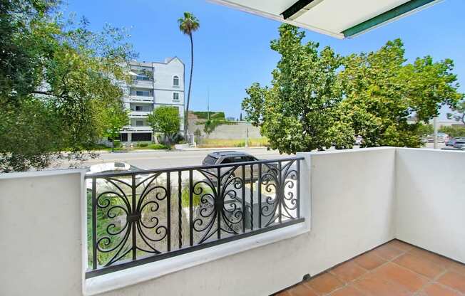 a balcony with a car parked on the street next to a wall and a railing