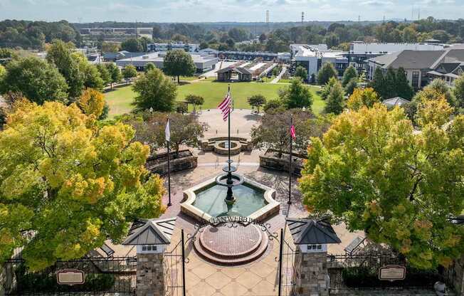 A fountain is in the middle of a plaza with a flag on top of a pole.