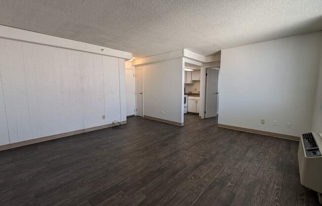 an empty living room with wood floors and white walls